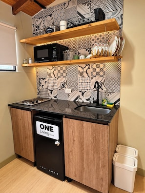 A compact kitchen with a black dishwasher, wooden cabinets, and patterned backsplash tiles.
