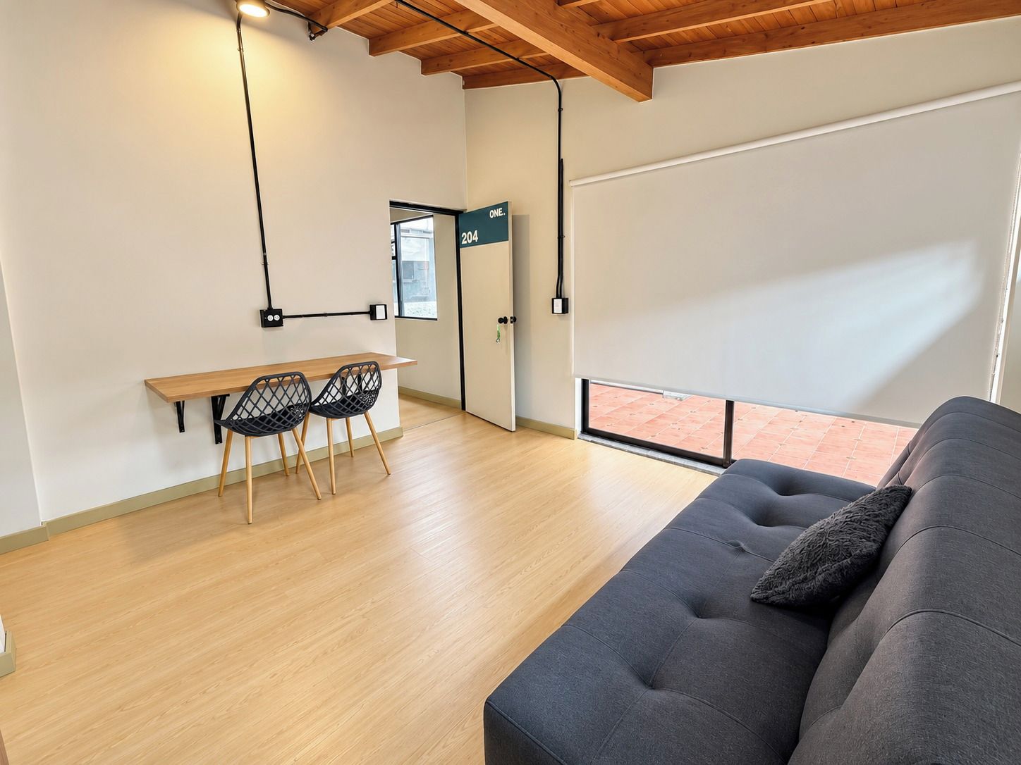 A modern interior with a sofa, a dining table with chairs, and a large window.