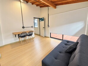 Un interior modern amb un sofà, una taula de dinar amb caires i una finestra gran.
