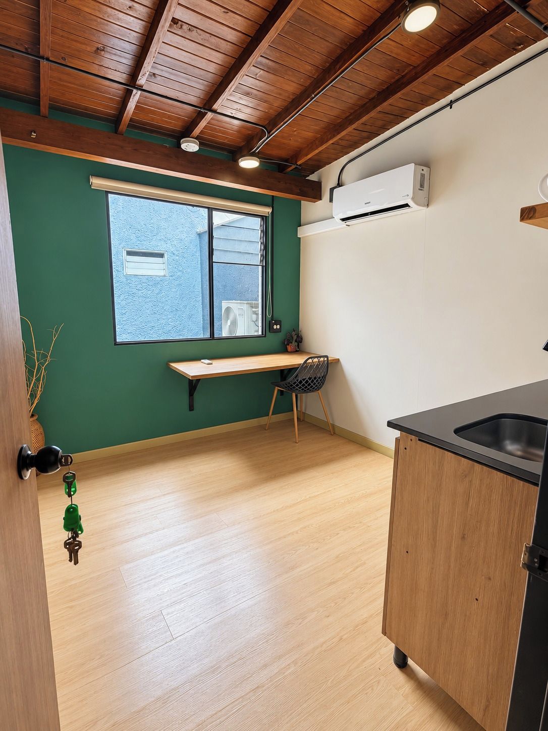 Eine kleine Küche mit Fenster, Spüle und integrierter Klimaanlage.