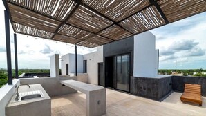 Eine Terrasse im Freien mit einem Betonschrank, einer Holzbank und einer Pergola.