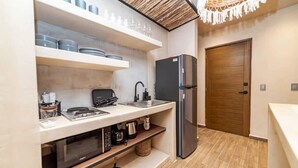 Une cuisine compacte équipée d’un four encastré, d’un four à micro-ondes et d’un réfrigérateur en acier inoxydable.