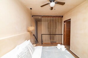 A bedroom with a bed, a ceiling fan, a hanging light fixture, and a sliding door.