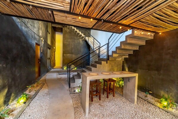 A modern interior with a concrete staircase, a table with stools, and a ceiling made of wooden slats.