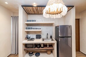 A compact kitchenette with a built-in microwave, toaster, sink, and a stainless steel refrigerator.