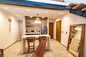 A modern kitchen with a dining area, wooden furniture, and a chandelier.