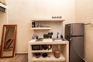 A compact kitchen with a built-in microwave, coffee maker, and a sink.