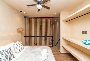 Una camera da letto moderna con un letto, una ventola a soffitto, un pannello intrecciato e scaffalature a muro.