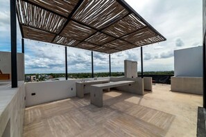 Une terrasse sur le toit, agrémentée d’une pergola en bois, de bancs en béton et offrant une vue sur le paysage urbain.
