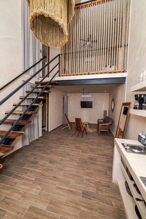 A loft-style room with a wooden staircase, a hanging light fixture, and a loft bed with a rope barrier. - Downtown Tulum Loft w/Rooftop Pool (Tulum)