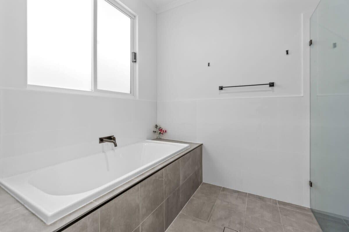 A modern bathroom with a large bathtub, a window, and a shower area.