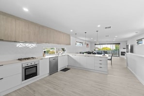 A modern kitchen with white cabinetry, a gas stove, and a dishwasher.