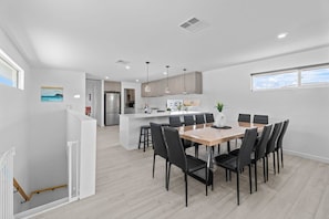 A modern kitchen with a central island, dining area with chairs, and a view of the city.