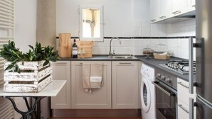 A compact kitchen with a washing machine, a sink, and a stove.
