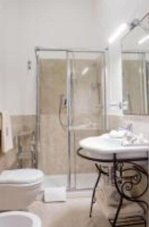 Et moderne badeværelse med en glasbrusekabine, en rund vask med et buet design og et hvidt toilet.