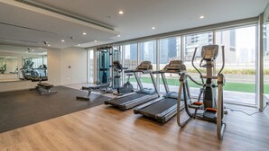 A gym with treadmills, elliptical machines, and weight equipment. - Relaxing 2BR at Vera Residences (Dubai)