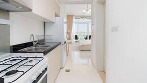 A modern kitchen with a gas stove, a sink, and a window overlooking a balcony. - Elegant Studio at Damac Hills Carson B (Dubai)