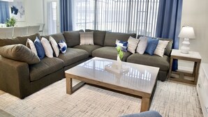 A modern living room with a sectional sofa, a glass coffee table, and a side table with a lamp. - Villa near Disney 5 bd/4.5bth home 335 (Davenport)