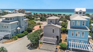 A coastal residential area with multi-story houses, a clear view of the ocean, and a well-maintained road.