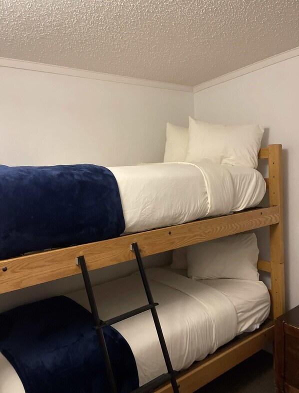 A bunk bed with a wooden frame and white bedding.