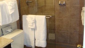 Un baño con ducha de mampara, inodoro y lavamanos con toallero.