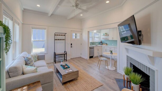 A spacious living room with a sofa, coffee table, and a TV mounted on the wall. - Walk to Beach and Town, Fire Pit, BBQ (Bungalows123) (Ocean Park)