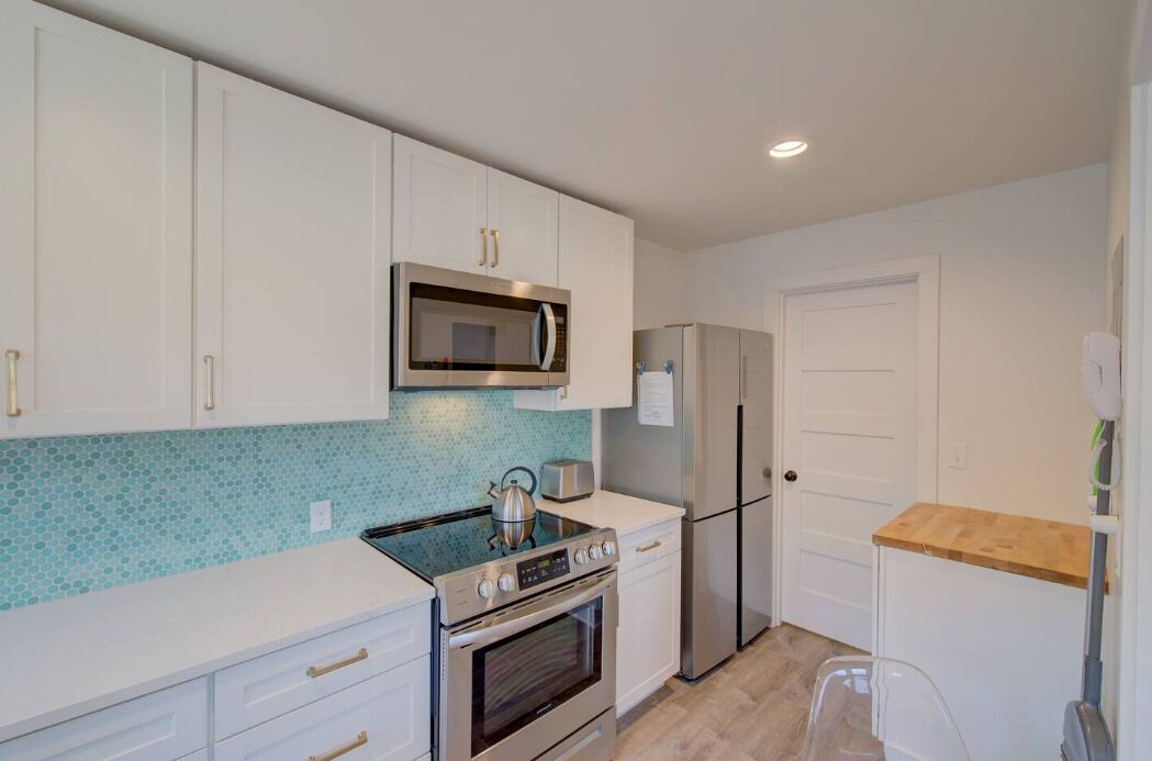 A compact kitchen with white cabinets, a microwave, a refrigerator, a stove, and a toaster.