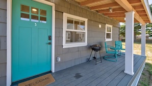 A house with a turquoise door, a porch with chairs, and a grill. - Walk to Beach and Town, Fire Pit, BBQ (Bungalows123) (Ocean Park)