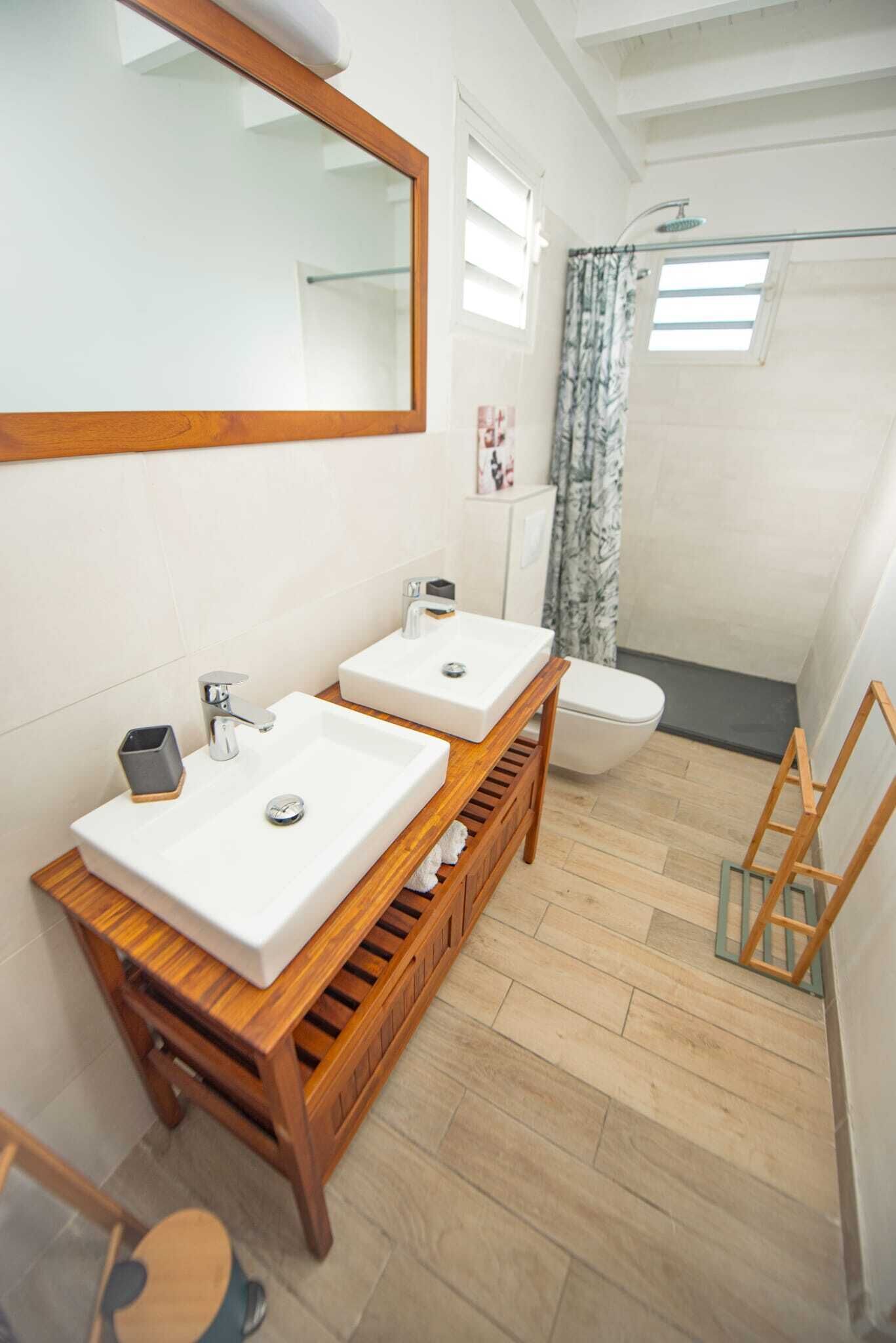 Un baño con dos lavabos, un espejo, un inodoro y una ducha.