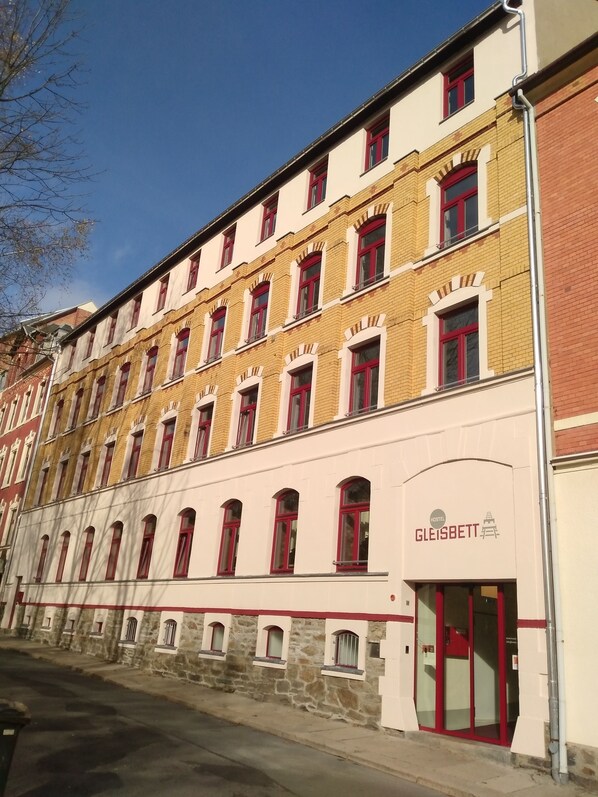 Un immeuble à plusieurs étages, avec une rangée de fenêtres et une enseigne indiquant l’hôtel « Gleisbett ».