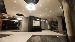 A modern lobby with a large abstract artwork, recessed lighting, and a staircase.