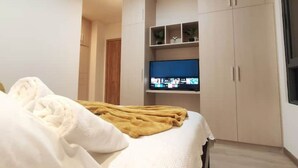 A bedroom with a bed, a TV on a shelf, and a wardrobe.