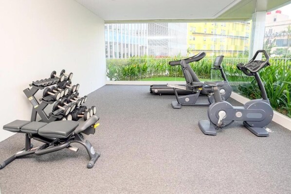 A gym with treadmills, elliptical machines, and weight benches.