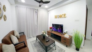 Una sala de estar moderna con sofá, mesa de centro, televisor y elementos decorativos.