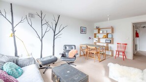 En moderne stue med sofa, lænestole, spisebord og reol.
