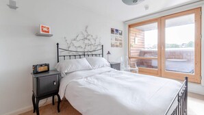 Et soveværelse med en seng, et natbord, en lampe og et stort vindue med udsigt.