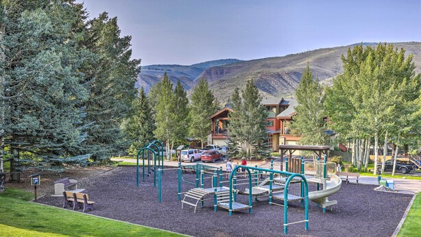 A playground with climbing structures and a slide, surrounded by trees and a building with a sloped roof. - Rocky Mountain Retreat: 2 Mi to Beaver Creek! (Avon)