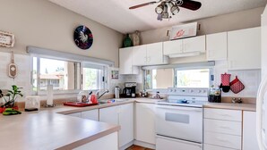 Una cocina moderna con armarios blancos, una estufa y un ventilador de techo.
