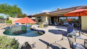 Un jardin avec une piscine, du mobilier d’extérieur et des parasols.
