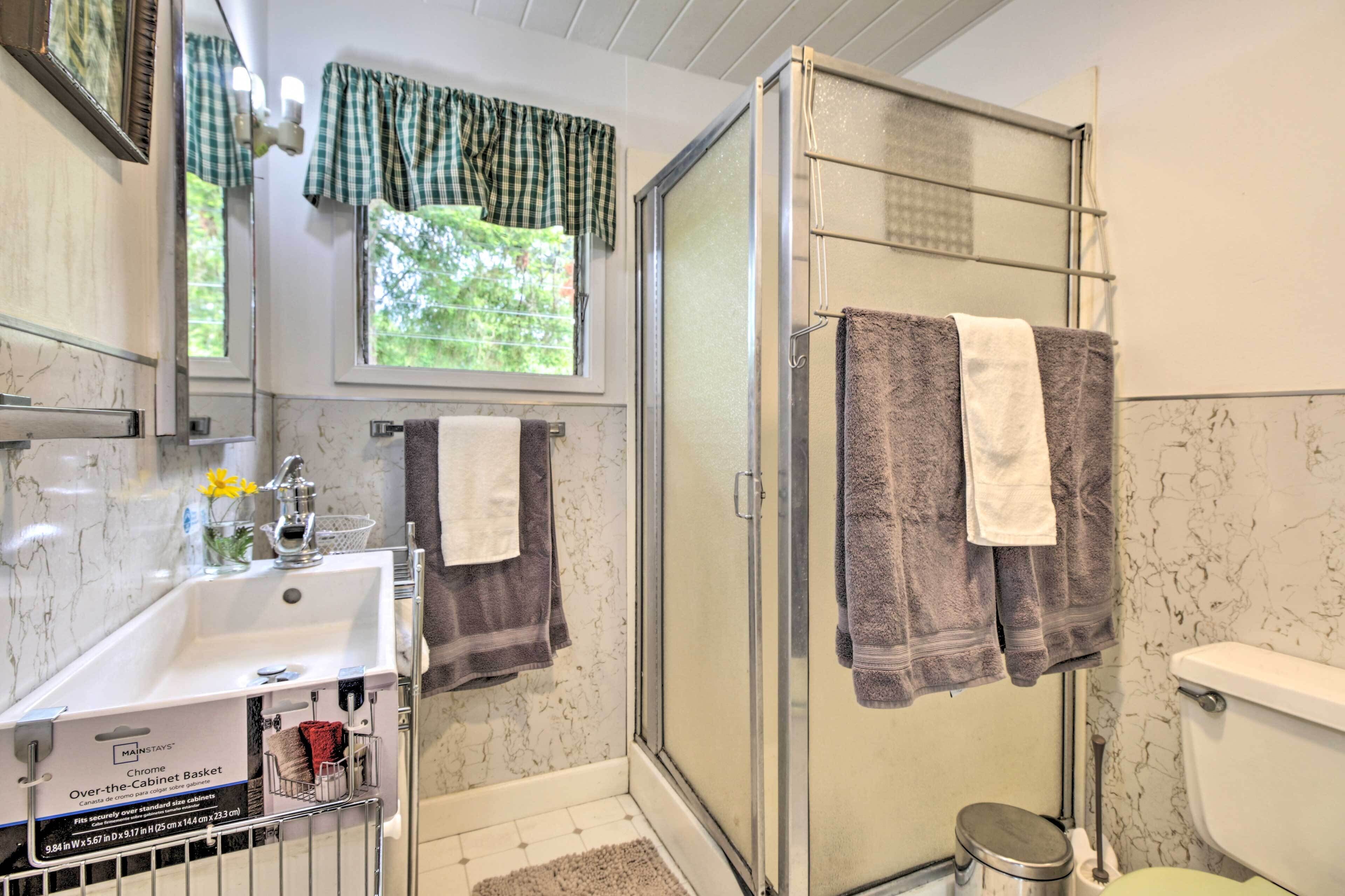 Une salle de bain avec une douche, un lavabo et des toilettes. Un porte-serviettes chromé est fixé au-dessus des meubles.