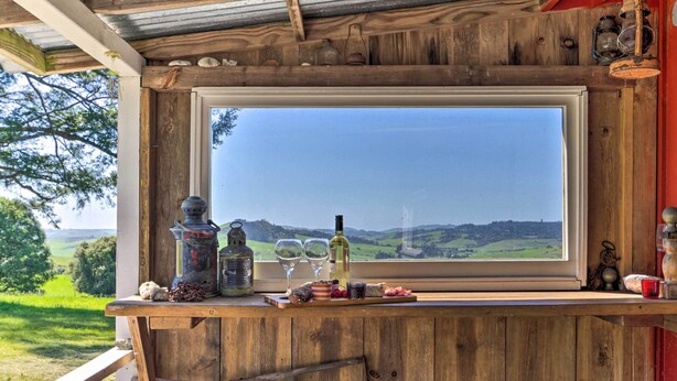 Un área con barra de madera y un ventanal grande con vistas a un paisaje verde.