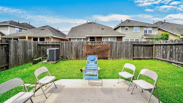 A backyard with a concrete patio, a wooden fence, and a row of houses in the background. - Spacious Stay at a Houston Getaway w/ Fireplace! (Houston)