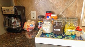 A kitchen counter with a coffee maker, coffee pods, sugar, ground coffee, and sweetener. - Spacious Stay at a Houston Getaway w/ Fireplace! (Houston)