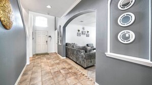 A hallway with a grey wall, a grey sofa, and a white door. - Spacious Stay at a Houston Getaway w/ Fireplace! (Houston)