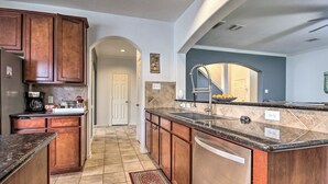 A kitchen with wooden cabinets, a granite countertop, a stainless steel sink, and a tiled backsplash. - Spacious Stay at a Houston Getaway w/ Fireplace! (Houston)