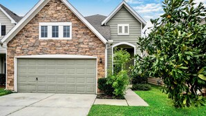A residential house with a stone facade, a garage, and a well-maintained lawn. - Spacious Stay at a Houston Getaway w/ Fireplace! (Houston)