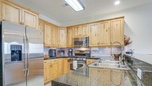 A modern kitchen with wooden cabinets, stainless steel appliances, granite countertops, and a built-in oven.