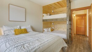 A room with a bunk bed, a ceiling fan, and a framed artwork on the wall.