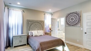 A bedroom with a bed, nightstand, dresser, and a large decorative wall piece.