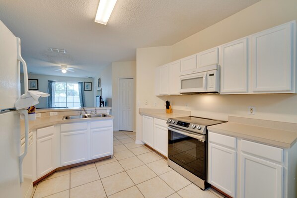 A kitchen with white cabinets, a microwave, an oven, and a sink. - Private Lanai! Gated Davenport Retreat (Davenport)
